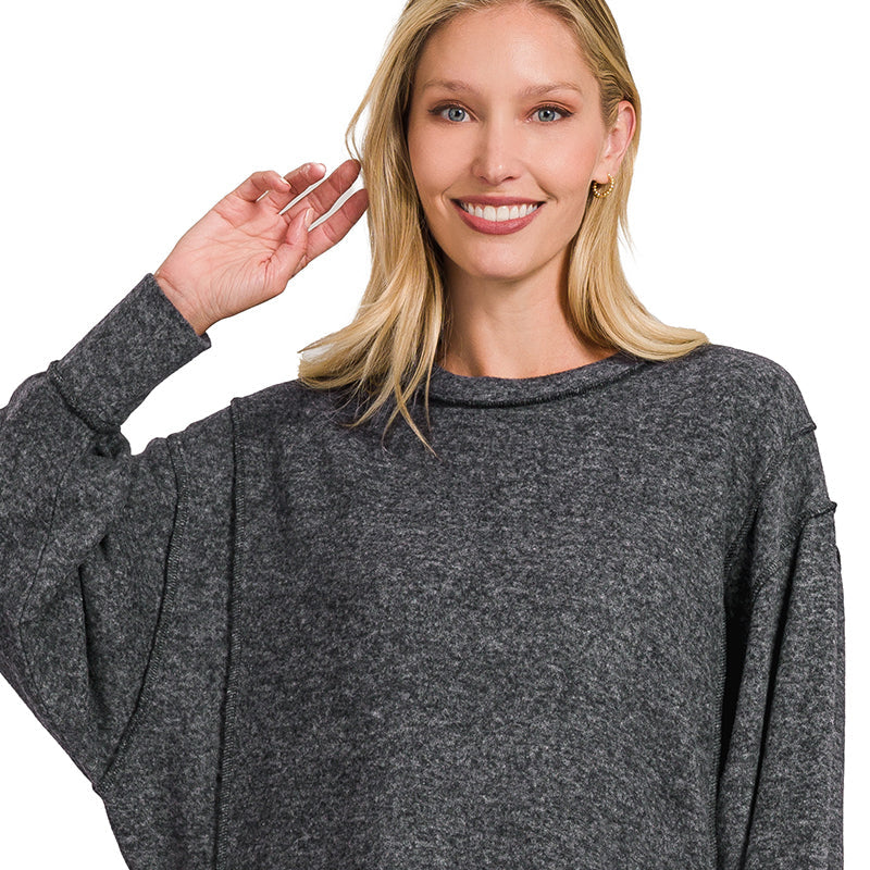 Woman wearing a gray sweater and blue jeans on a white background
