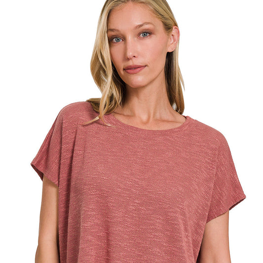 Woman wearing a rust-colored top and blue jeans on a white background