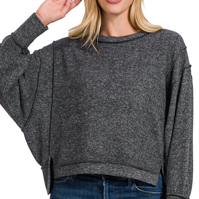Woman wearing a gray sweater and blue jeans on a white background