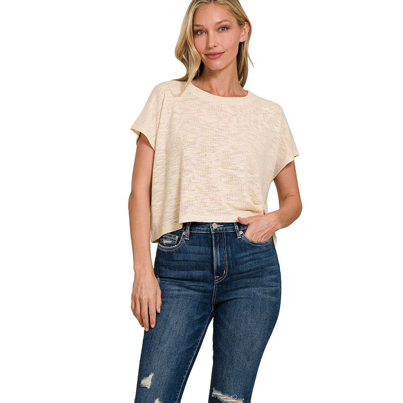 Woman wearing a beige top and blue jeans on a white background