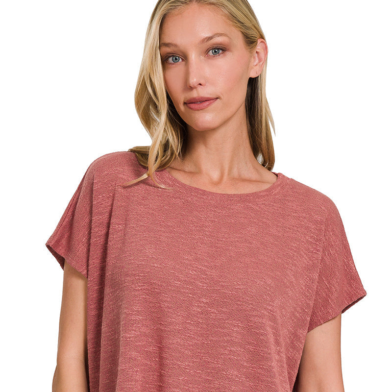 Woman wearing a rust-colored top and blue jeans on a white background