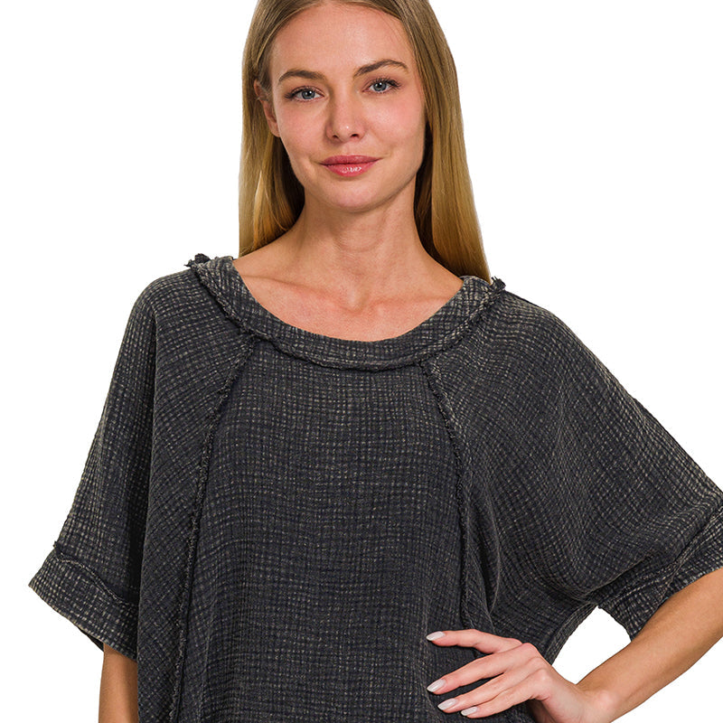 Woman wearing an ash black textured top with a plain background