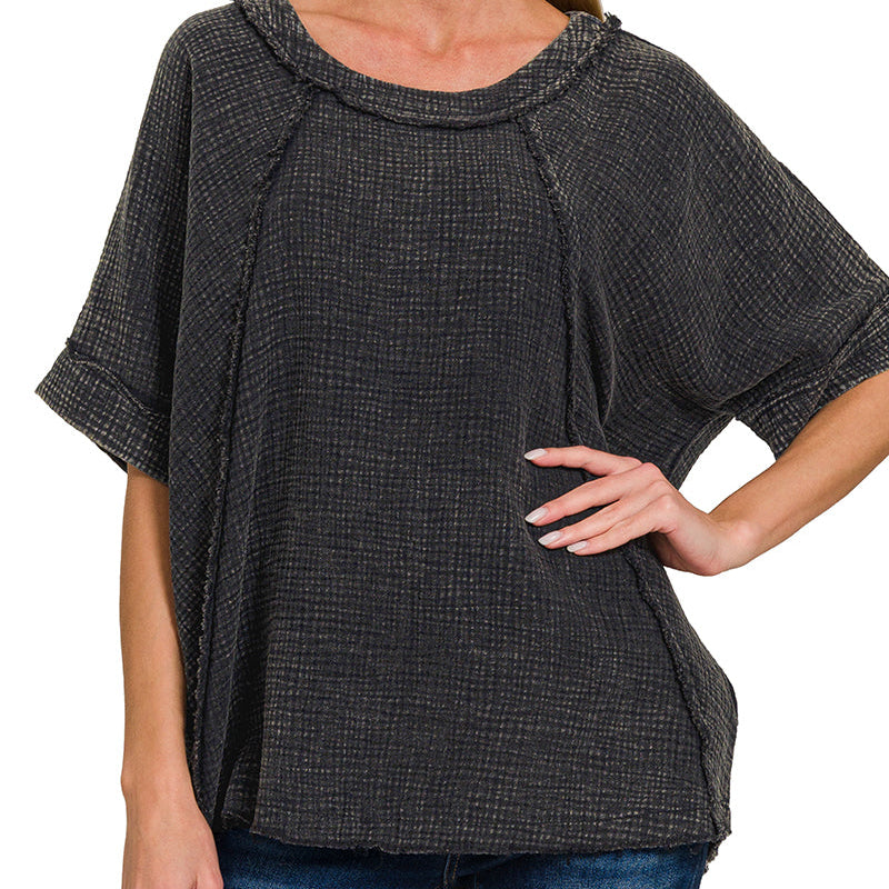 Woman wearing an ash black textured top with a plain background