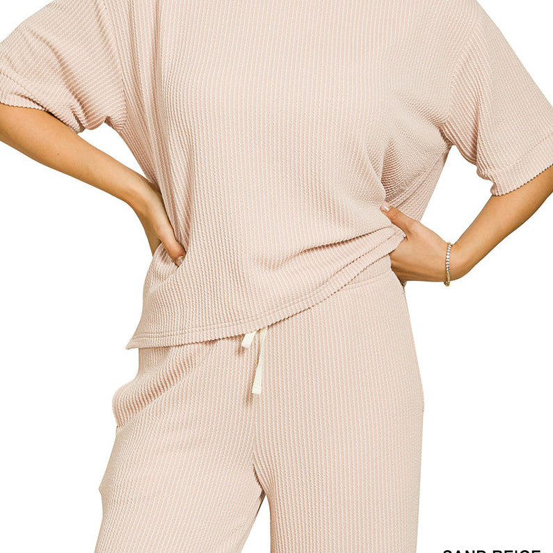 Woman wearing a sand beige ribbed lounge set on a white background